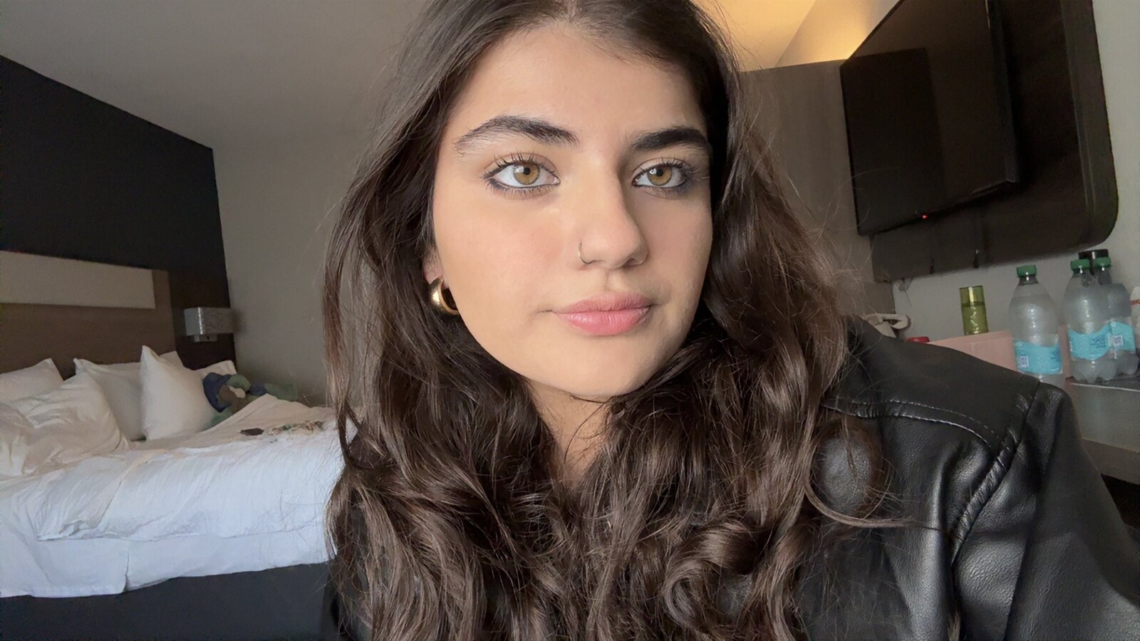 Radhika today: long dark curls, gold hoops and a black leather jacket